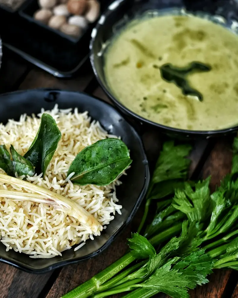 Bowls of curry, rice and whole spices on a dark table
