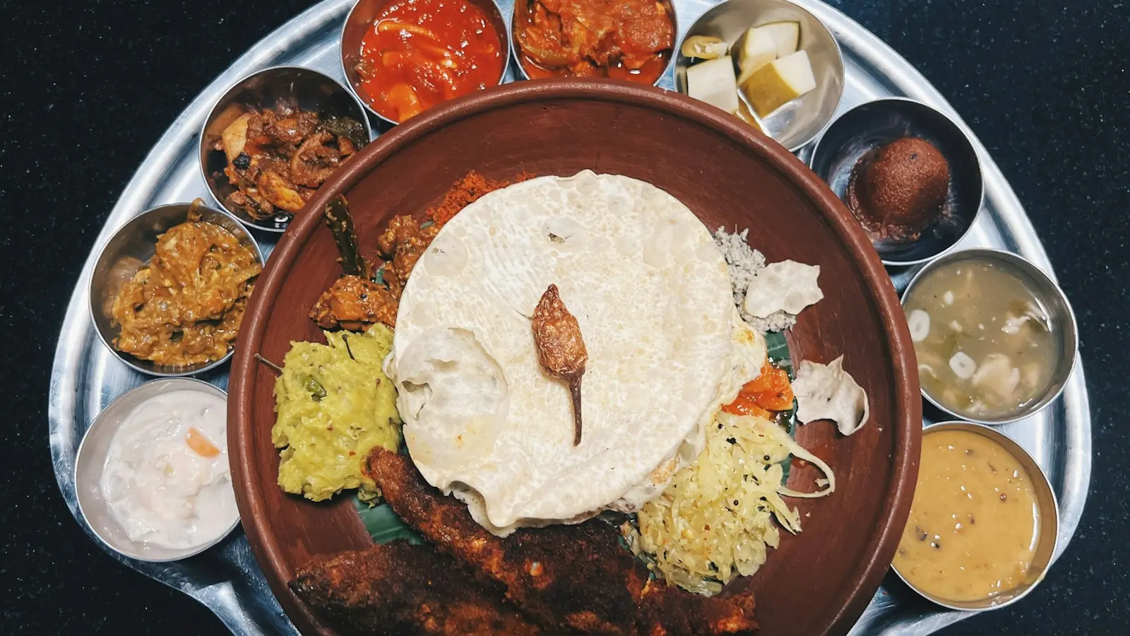 A Kerala thali with fried fish, rice, pappadam and small bowls of curry